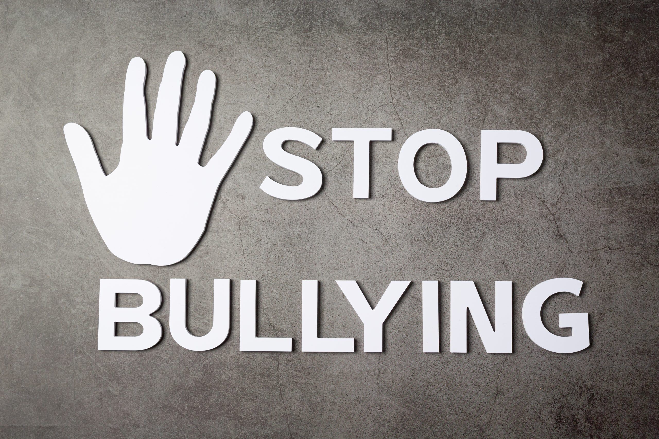 word "stop bullying" with hand sign on dark background apoyo escolar madrid